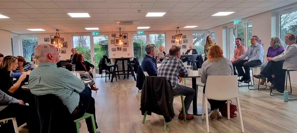 room of people with their backs to the camera looking at a panel of 4 people
