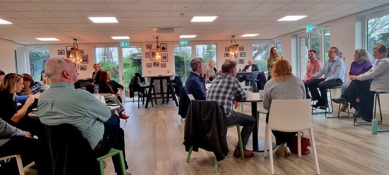 groups of people sitting at tables with their backs to the camera, facing a panel discussion.
